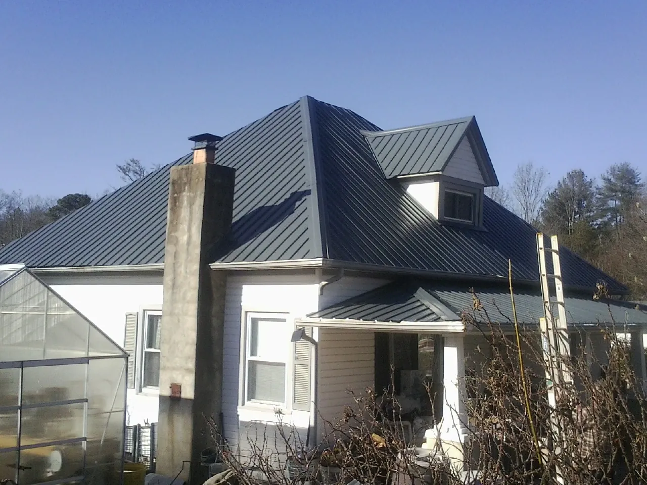 Dark blue standing seam metal roof on a white farmhouse with dormer — Slate & Tile Roof Repair by Roofing Brothers in Shrewsbury