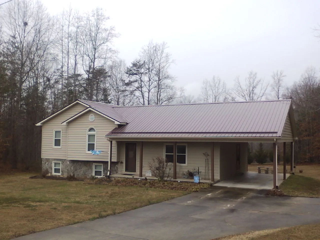 Burgundy metal roof on a tan split level home with an attached carport in Shrewsbury